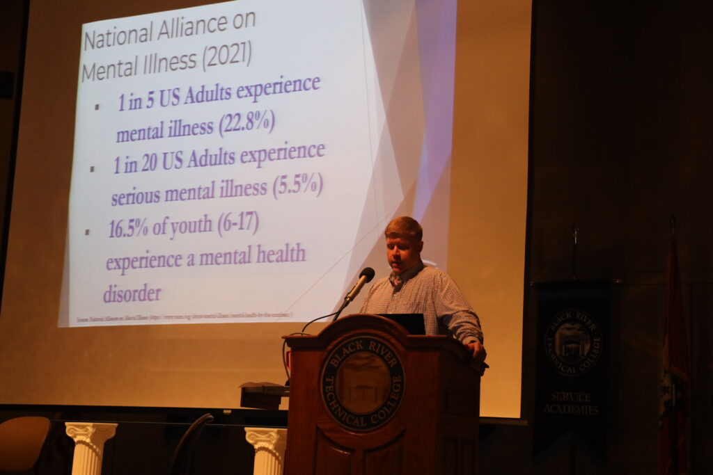 Man standing at a podium with a slideshow behind him.