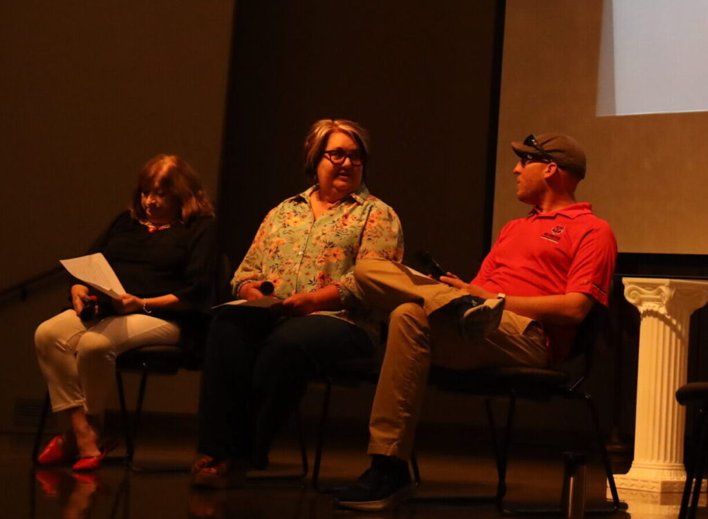 A group of people on a stage talking during a professional development session.