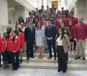 Students from across Arkansas community colleges, many wearing red blazers, pose on a marble staircase with Arkansas Governor Sarah Sanders during the ACC Student Leadership Academy.